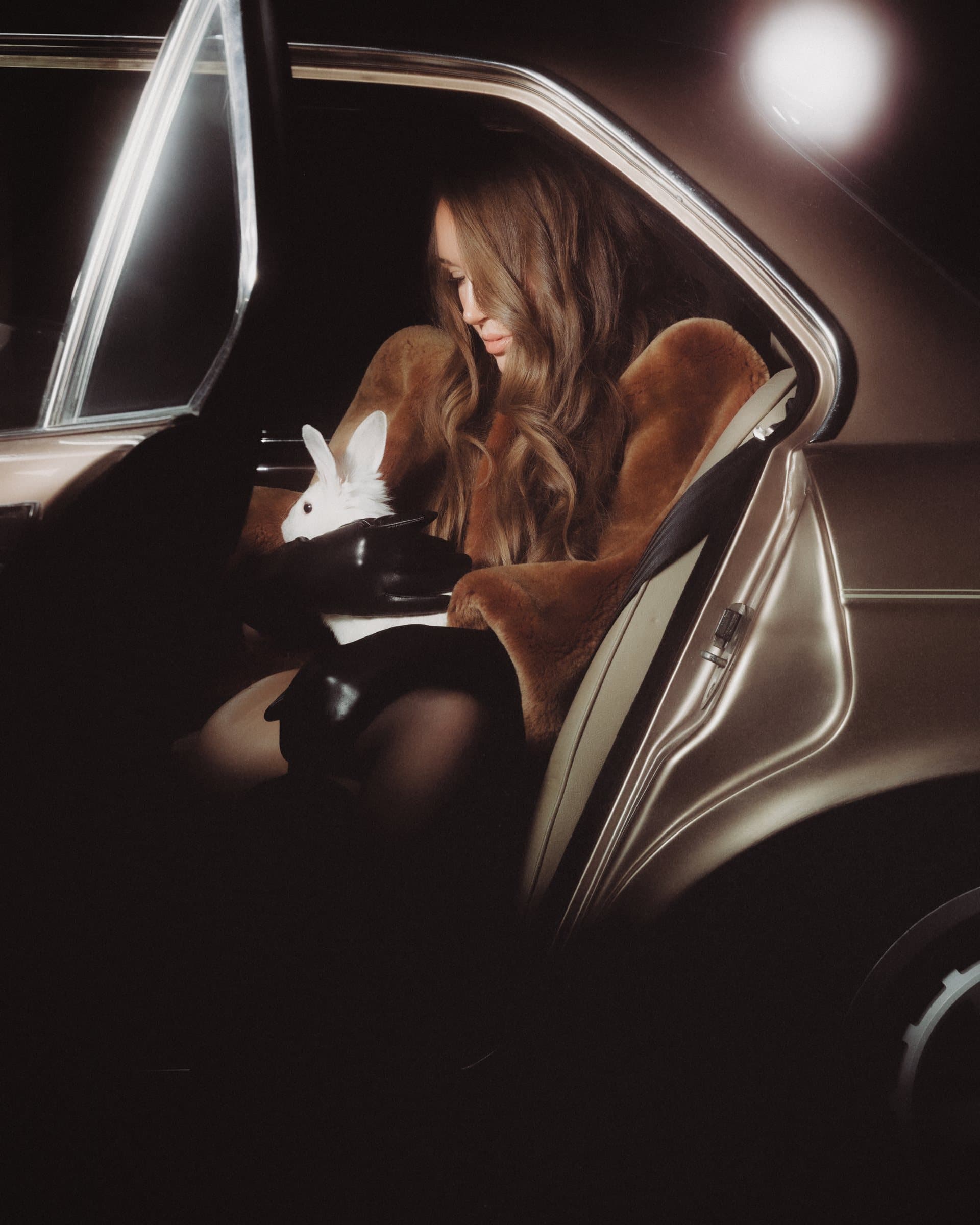 Katharine Fountain in the back seat, door open, the white rabbit in her gloved hands